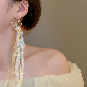 Gros plan de boucles d'oreilles étoile à pompons avec ruban coloré sur le mannequin