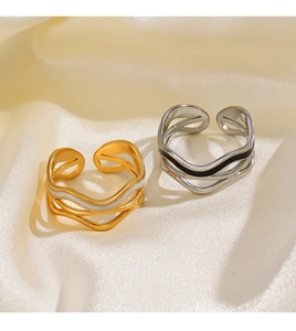 Close-up of wavy hollow cross ring in gold and silver finish on yellow silk