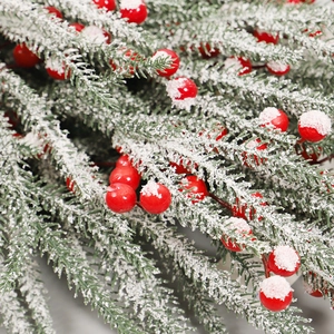 Christmas garland with green pine needles, red holly berries and artificial snow effect