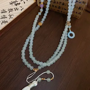 Blue glass bead necklace with silk tassel and gold accents on a rustic wooden background