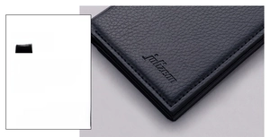 Macro shot of black lychee grain leather wallet with precision stitching and embossed logo