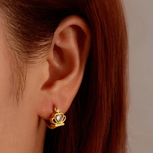 18K gold plated crown earrings with heart zirconia worn by a model in a close-up view