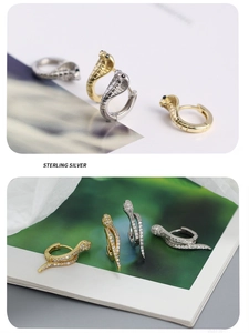 Macro detail of sterling silver snake earrings in gold and silver with zircon settings