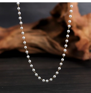 Macro shot of elegant white pearls with gold chain links on a vintage wood background