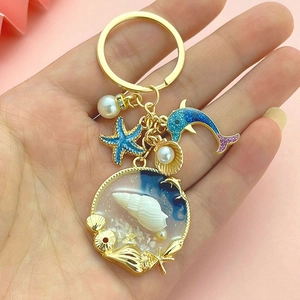 Golden keychain with blue dolphin, starfish, and shell resin pendant for bags