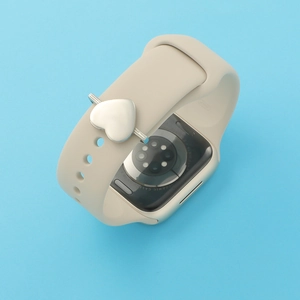 Close-up of silver heart-shaped metal charm on a beige silicone smartwatch strap