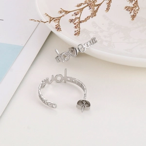 Detailed view of silver C-shaped earrings featuring a hollow 'love' lettering design