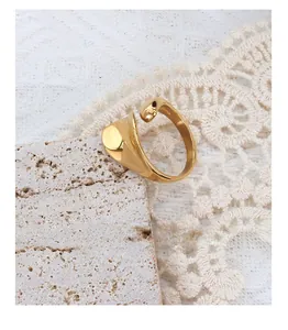 Close-up of a French style asymmetric gold plated ring on white lace and stone
