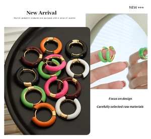 Close-up of colorful enamel geometric gold earrings shown on tray and worn by a model