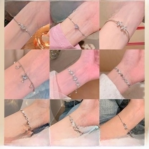 Detailed view of S925 silver charm bracelets with butterfly and heart pendants on wrist