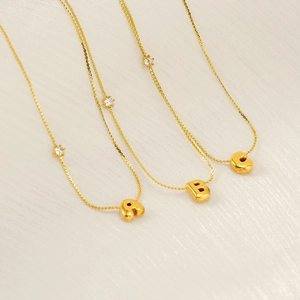 Detail of 3D gold initial necklaces A B C with tiny round zircon and polished finish