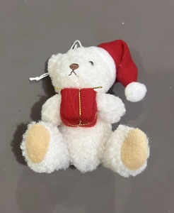 Detail of white plush Christmas bear ornament with red hat and festive gift box