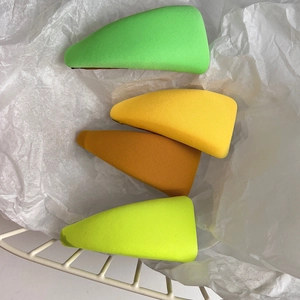 Detail of four colorful fabric-wrapped triangle BB hair clips in a white wire basket
