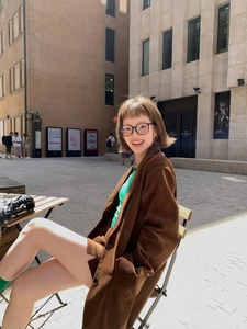 Detailed view of women's caramel corduroy blazer worn by a model in a street setting
