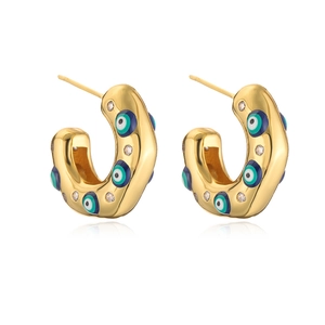 Irregular C-shaped gold earrings with evil eye enamel patterns and white stones