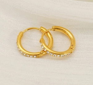 Detailed view of 18K gold plated titanium steel hoop earrings with crystals on white fabric