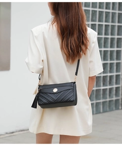 Detail shot of black chevron quilted soft leather crossbody bag with tassel and gold hardware.