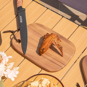Portable acacia wood cutting board with roasted chicken wings for outdoor camping setup