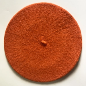 Detailed top view of the soft knitted texture and orange beret hat with a small stem
