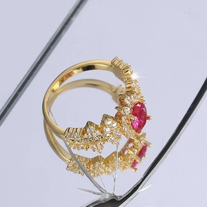 Elegant gold ring with oval red gemstone and white zircon accents on a textured surface