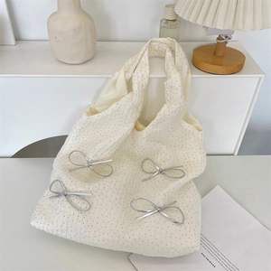 Dettaglio della borsa tote crema a pois con fiocco d'argento in un ambiente elegante