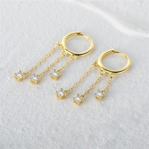 Detailed view of gold tassel earrings featuring dangling chains with round cubic zirconia