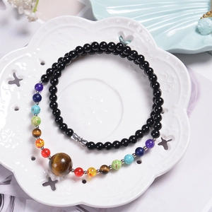 Detail of 6mm black beaded necklace with colorful chakra stones and tiger eye pendant