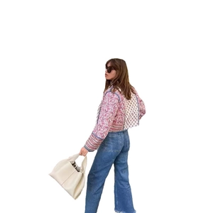 Women reversible floral quilted jacket paired with blue jeans and beige leather tote bag