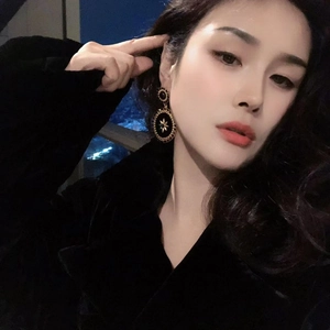 Retro matte gold geometric earrings with black enamel and gold star detail on model