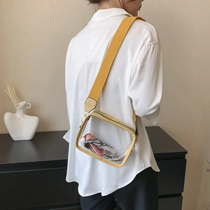 Side view of clear PVC crossbody bag with yellow strap shown on a model for scale