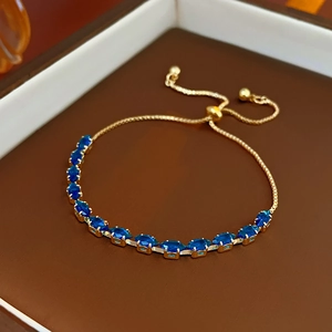 Macro shot of gold-plated sliding bracelet with faceted deep blue zircon stones