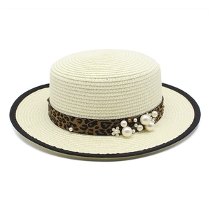 Detail of straw sun hat featuring leopard print ribbon with pearls and flower accents