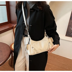 Detail of ivory faux leather shoulder bag with sleek metal zipper and long strap on model