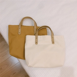 Close-up of minimalist canvas tote bags in ginger and cream with leather handles