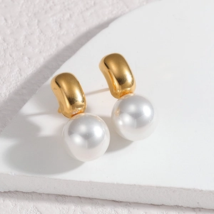 Detail of elegant pearl drop earring with curved gold-plated titanium steel on stone surface
