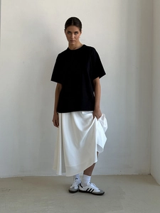 Full view of high waist satin A-line maxi skirt in white with black minimalist t-shirt