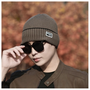Detail of a brown ribbed knit beanie with stylish logo patch and warm winter texture