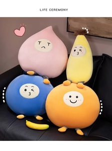 Detail showing soft fruit plush toys with cute embroidered faces on a black sofa