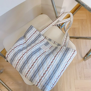 Gros plan du sac cabas matelassé avec motif cerise et étiquette sur une chaise