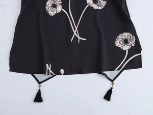 Detail of black printed top hem featuring wooden beads and decorative black tassels