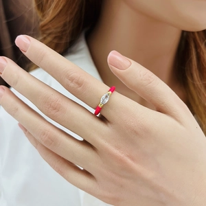Close-up of golden ring with red enamel and marquise-cut crystal on a model's finger