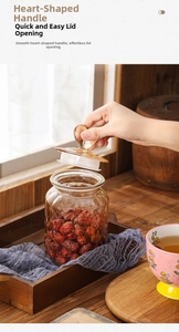 Detail of amber glass storage jar with heart handle lid filled with red dates
