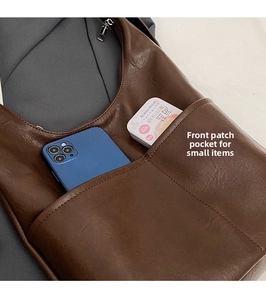 Close-up of leather tote bag front pocket showing phone storage and fine stitching