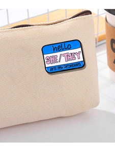 Detail of Hello She/They pronouns enamel pin badge on a beige canvas zipper bag