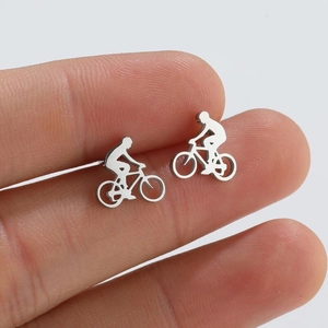 Polished silver cyclist stud earrings held to show scale and detailed bike design