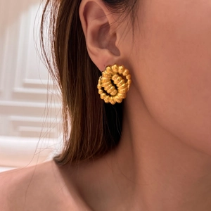 Close-up of golden vintage twisted hoop earrings with pleated texture on a model