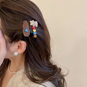 Detail view of flocked bear and heart hair clips on model with elegant pearl jewelry