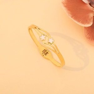 Gros plan du bracelet ouvert doré avec deux fleurs blanches et fermoir à ressort