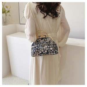Floral print shell bag detail showing golden chain strap and top handle on a model