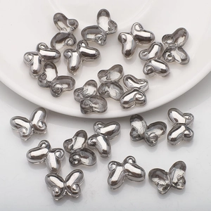 Close-up of 10x14mm silver butterfly glass beads scattered on a white ceramic plate